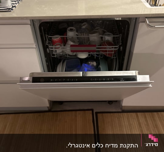 מדיח כלים פתוח עם כלים בפנים על רקע מטבח